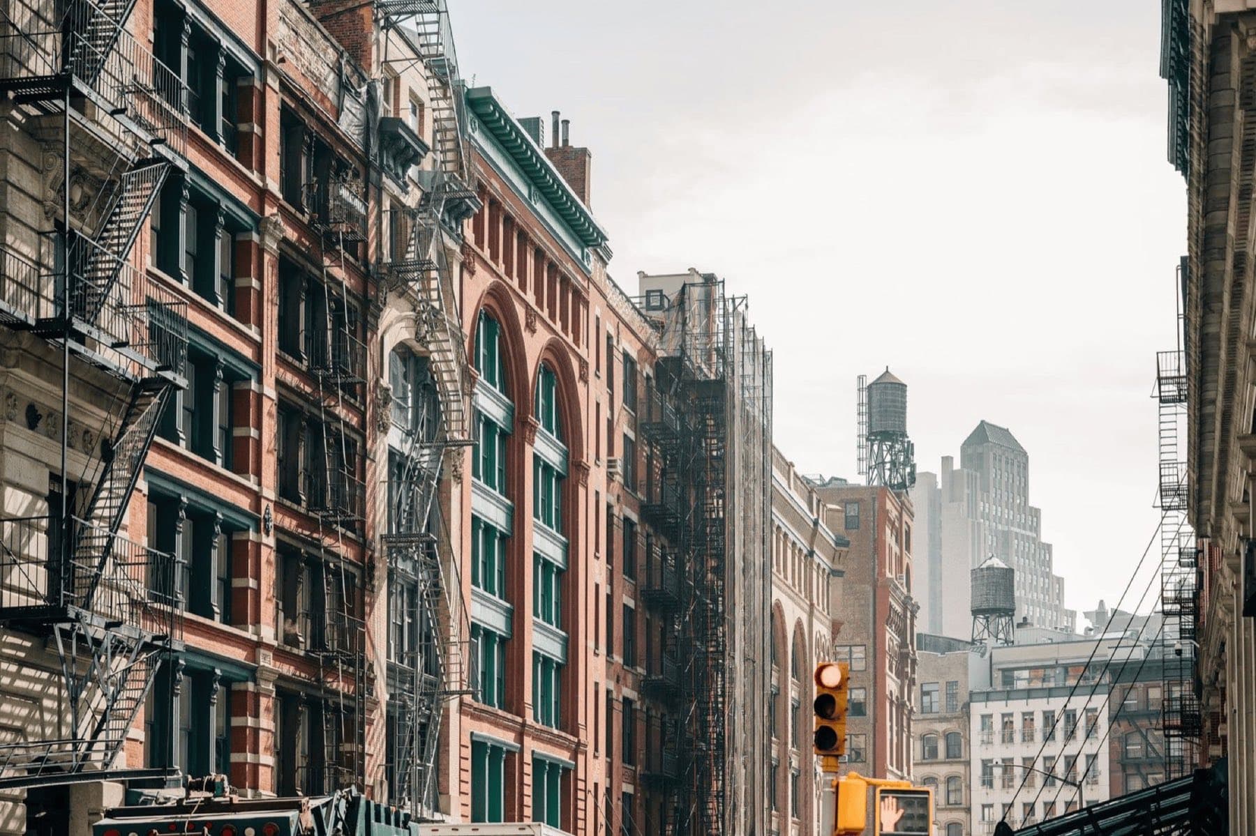 A brick street corner of New York with fire escapes on the buildings