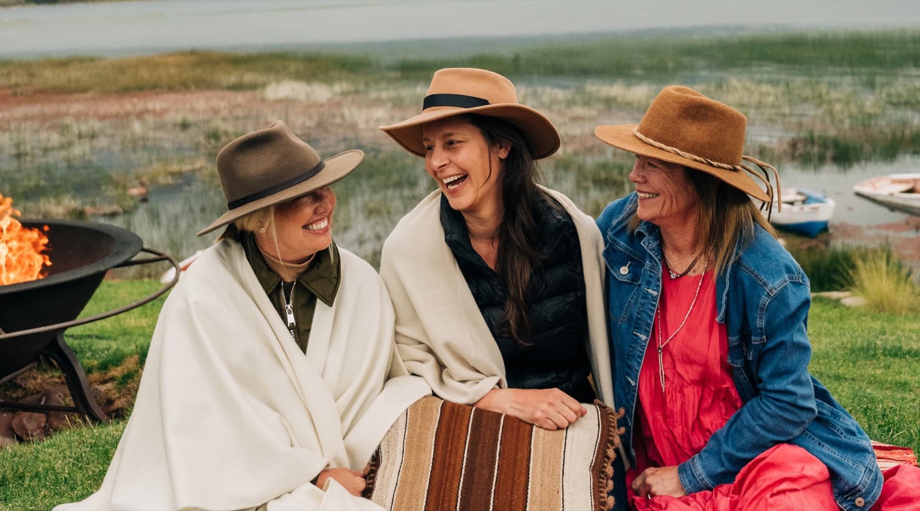 Three travel advisors laughing together on a picnic blanket